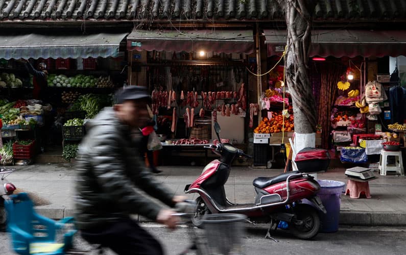 man on moped in front of market stalls