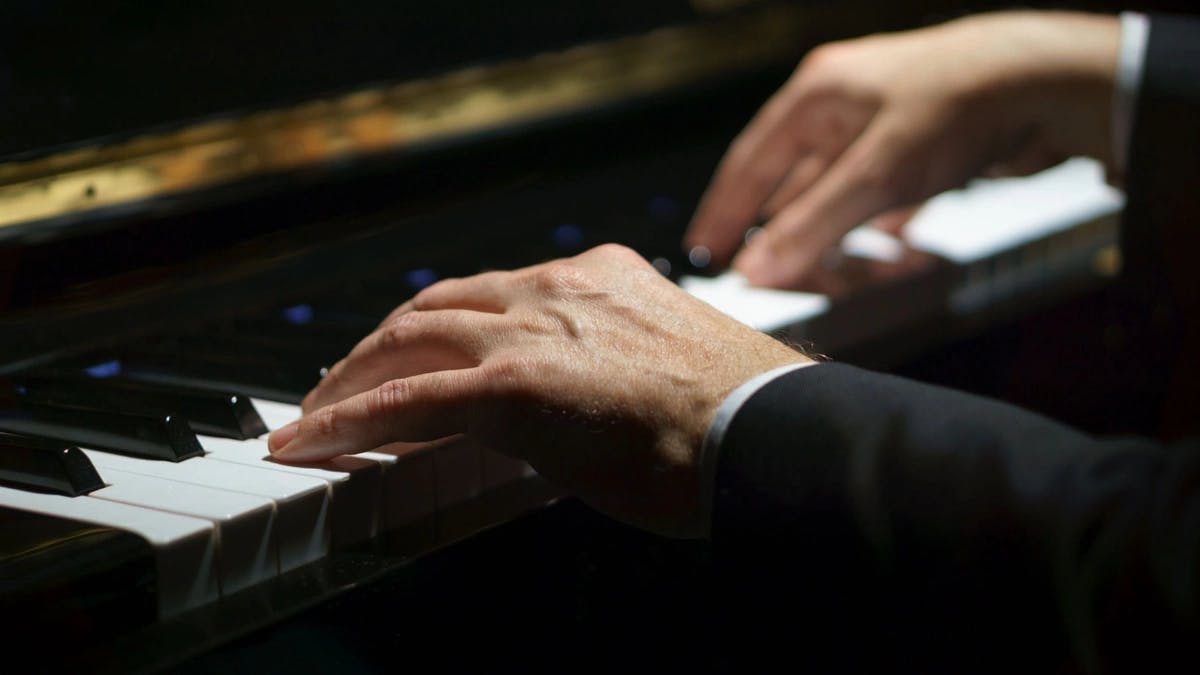 close up of a man's hands playing piano
