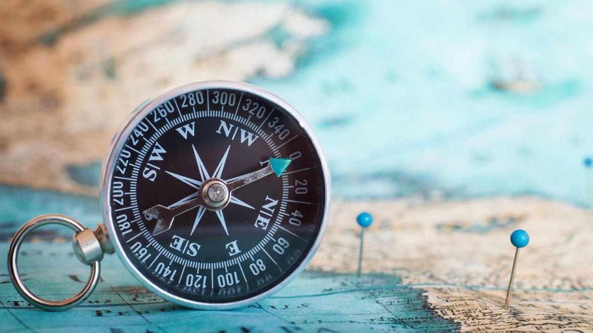 a compass sitting on a map with pins on it