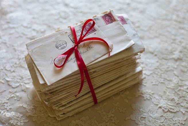 a stack of letters tied with a red ribbon