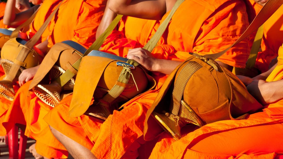 Sikhs dressed in bright orange outfits holding drums.